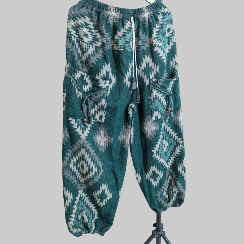 Green and gray patterned pants hanging on a wooden door.