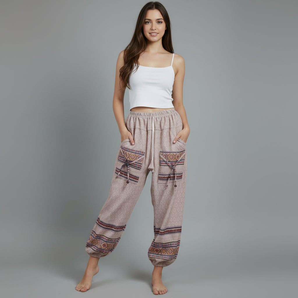 Woman wearing patterned harem pants and a white top on a gray background