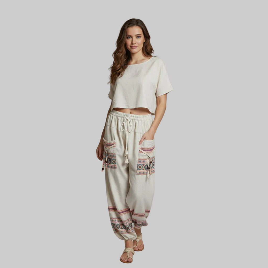 Woman wearing a white top and patterned pants on a plain background