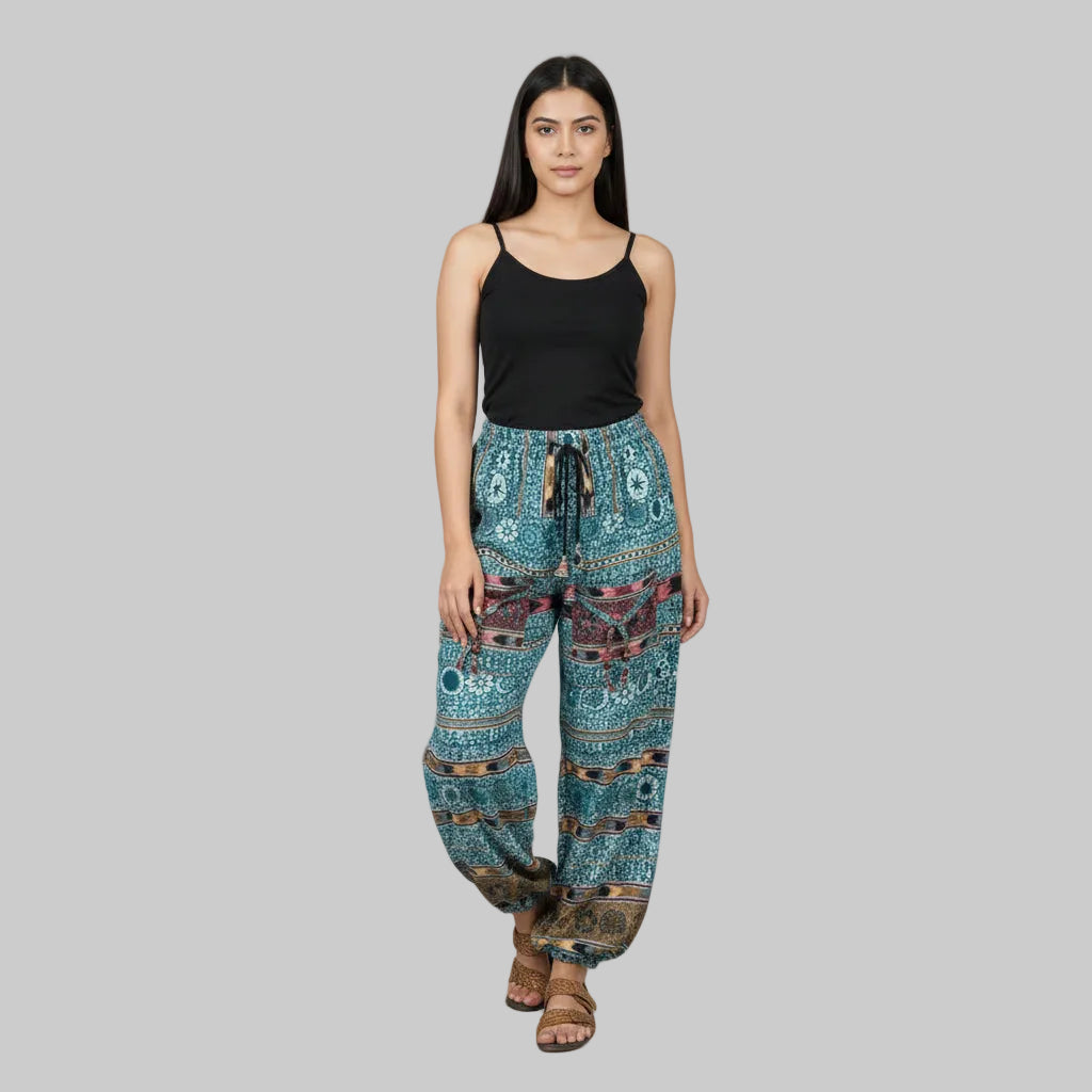 Woman wearing a black tank top and patterned blue pants on a gray background
