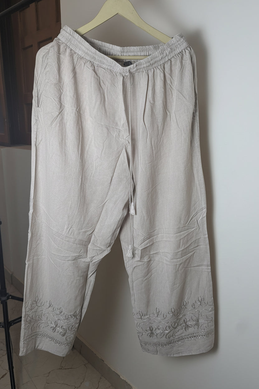 Beige pants hanging on a hanger against a white wall