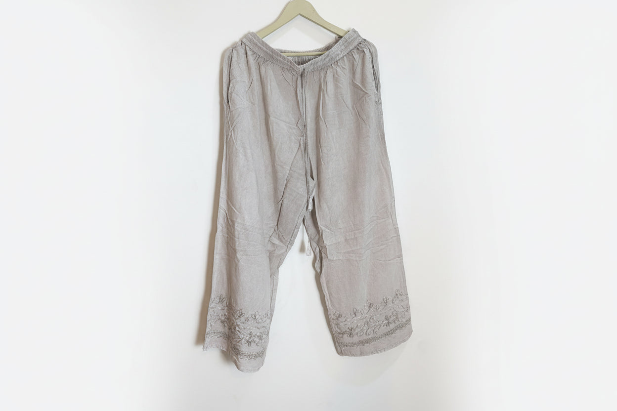 Light brown pants with lace trim on a white background