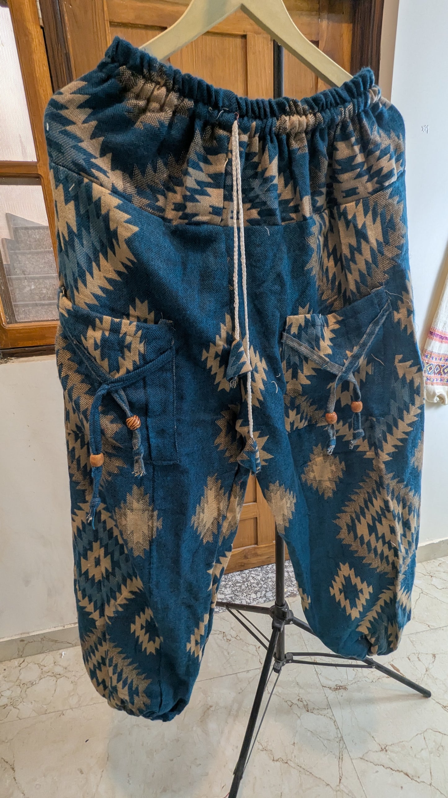 Blue patterned pants on a hanger against a neutral background