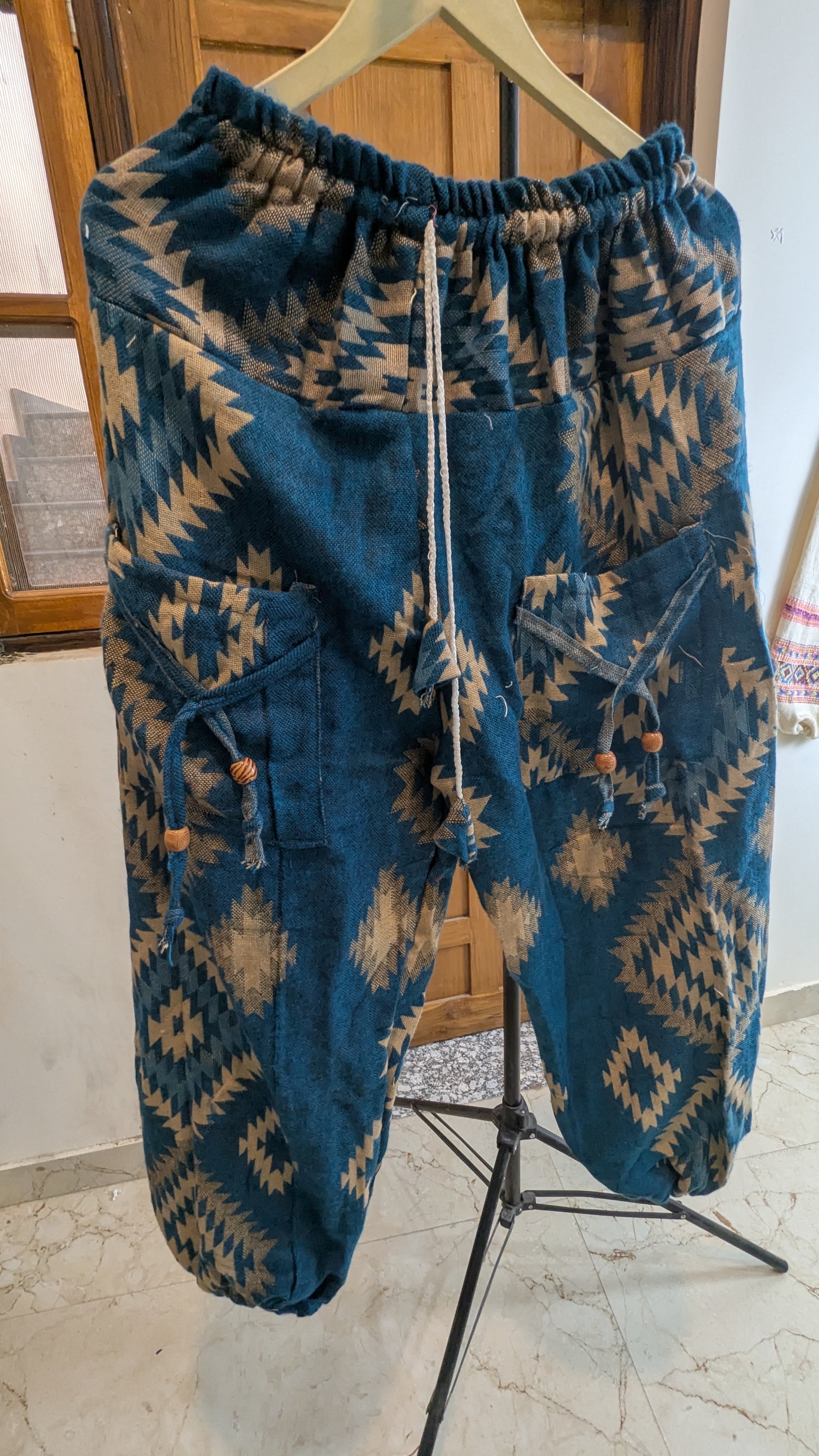 Blue patterned pants on a hanger against a neutral background